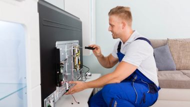 Young Male Electrician Repairing Television With Screwdriver